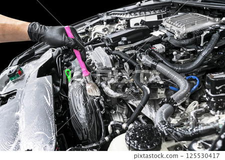 A man cleaning car engine with shampoo and brush. Car detailing or valeting concept. Selective focus. Car detailing. Cleaning with sponge. Worker cleaning. Car wash concept solution to clean A man cleaning car engine with shampoo and brush. Car detailing or valeting concept. Selective focus. Car detailing. Cleaning with sponge. Worker cleaning. Car wash concept solution to clean 125530417