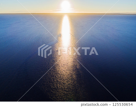 Aerial view of a Sunset sky background. Aerial Dramatic gold sunset sky with evening sky clouds over the sea. Stunning sky clouds in the sunset. Sky landscape. Aerial photography. 125530654