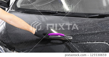 A man cleaning car with plastic sponge. Car detailing or valeting concept. Selective focus. Car detailing. Cleaning with sponge and cloth. Worker cleaning. Car wash concept solution to clean A man cleaning car with plastic sponge. Car detailing or valeting concept. Selective focus. Car detailing. Cleaning with sponge and cloth. Worker cleaning. Car wash concept solution to clean 125530659