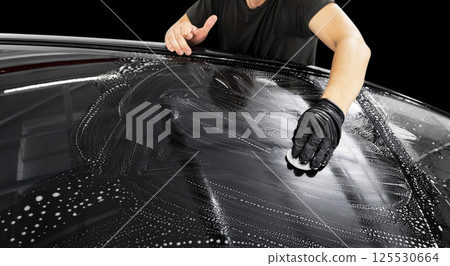 A man cleaning car with microfiber cloth. Car detailing or valeting concept. Selective focus. Car detailing. Cleaning with sponge. Worker cleaning. Car wash concept solution to clean 125530664