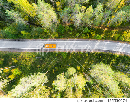Aerial view of a country road in the forest with moving cars. Beautiful landscape. Captured from above with a drone. Aerial bird's eye road with car. Aerial top view forest. Texture of forest view Aerial view of a country road in the forest with moving cars. Beautiful landscape. Captured from above with a drone. Aerial bird's eye road with car. Aerial top view forest. Texture of forest view 125530674