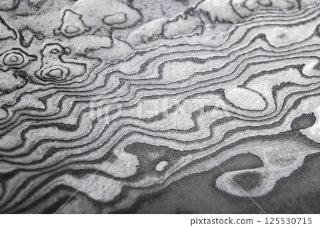 Background with pattern of damask steel. Close up. Macro shot of a damascus knife blade texture. Damascus steel pattern. Metal and steel background. Damascus steel with original pattern. 125530715