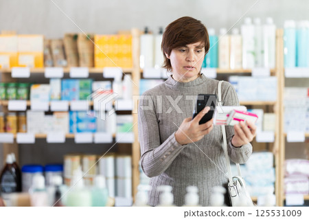 Woman scanning barcode on paracetamol boxes with phone at pharmacy Woman scanning barcode on paracetamol boxes with phone at pharmacy 125531009
