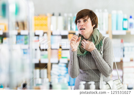 Woman suffering from severe cough in drugstore 125531027