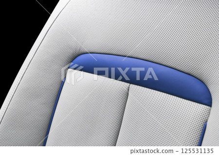 White leather interior of the luxury modern car. Perforated white leather comfortable seats with stitching isolated on black background. Modern car interior details. Car detailing. Car inside 125531135