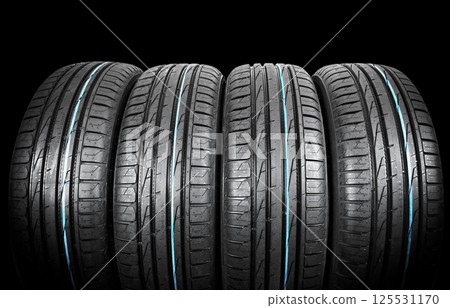 Studio shot of a set of summer car tires on black background. Tire stack background. Car tyre protector close up. Black rubber tire. Brand new car tires. Close up black tyre profile. Car tires in a 125531170