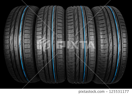 Studio shot of a set of summer car tires on black background. Tire stack background. Car tyre protector close up. Black rubber tire. Brand new car tires. Close up black tyre profile. Car tires in a 125531177