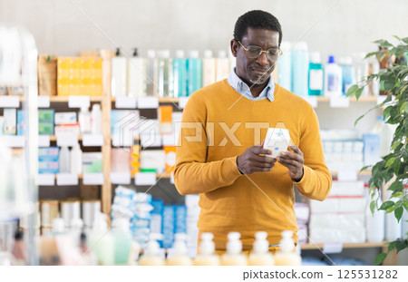 Adult man chooses pills at pharmacy Adult man chooses pills at pharmacy 125531282