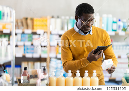 African American man scanning QR code on pills with phone in drugstore African American man scanning QR code on pills with phone in drugstore 125531305