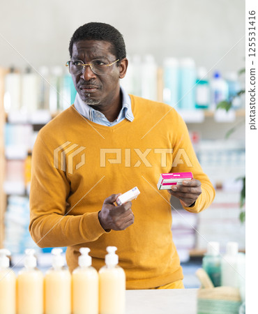 Adult man chooses paracetamol at pharmacy Adult man chooses paracetamol at pharmacy 125531416