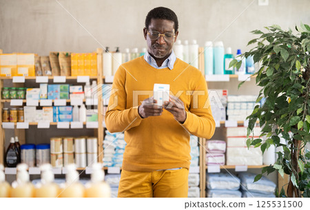 African man buyer select cream in drug store 125531500