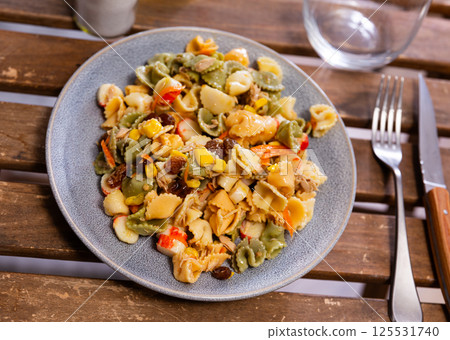 On wooden table made of planks there is plate with salad, cutlery, decanter with olive oil On wooden table made of planks there is plate with salad, cutlery, decanter with olive oil 125531740
