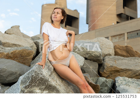 Portrait of relaxation female on stones at sea shore alone 125531753