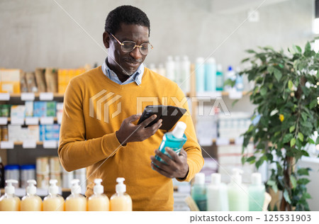 Man scanning mouthwash for ingredients and info in drugstore Man scanning mouthwash for ingredients and info in drugstore 125531903