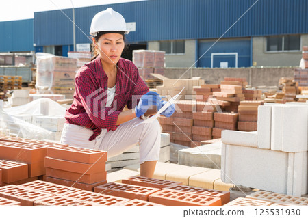 Woman with document in construction material storage 125531930