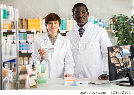 Male and female pharmacists offer pills 125532161