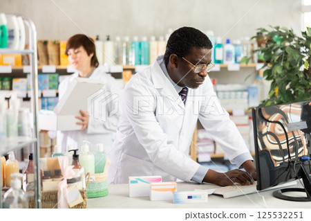 Male pharmacist working at computer in pharmacy Male pharmacist working at computer in pharmacy 125532251