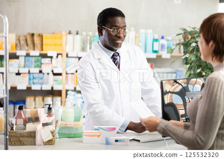Pharmacist searches for medicine on computer for female buyer 125532320
