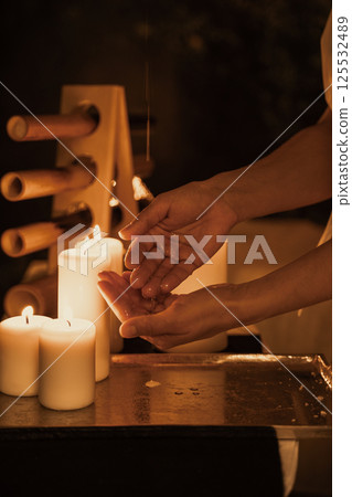 Hands Receiving Warm Oil Next to Lit Candles 125532489
