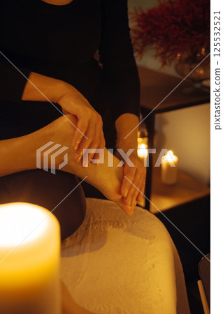 Relaxing Foot Massage Therapy in a Candlelit Room 125532521