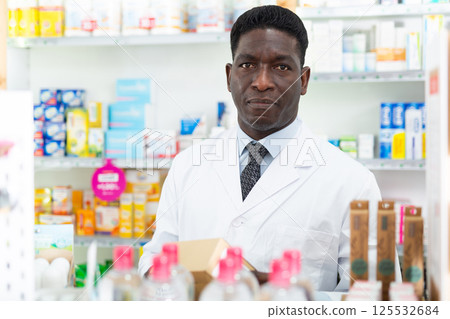 Portrait of an african american male pharmacist standing in the sales hall of a pharmacy Portrait of an african american male pharmacist standing in the sales hall of a pharmacy 125532684