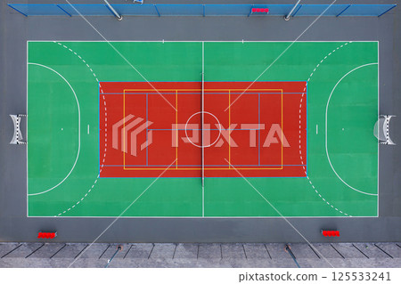 Aerial view of a vibrant basketball court with colorful markings in an urban setting 125533241
