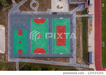 Aerial view of a multi-court sports facility with basketball and track areas at sunset 125533243