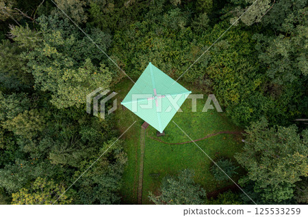 Overhead perspective of a observation tower cabin nestled in lush woodland during daylight hours. Overhead perspective of a observation tower cabin nestled in lush woodland during daylight hours. 125533259