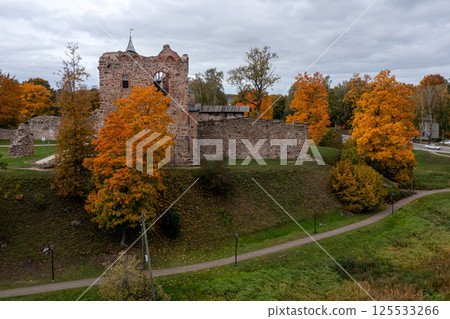 Ruins of an ancient castle surrounded by vibrant autumn trees in a tranquil landscape 125533266
