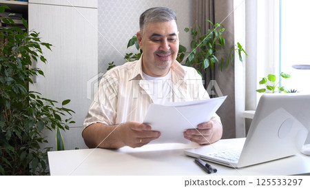 Man Reviewing Work Documents and Smiling Man Reviewing Work Documents and Smiling 125533297