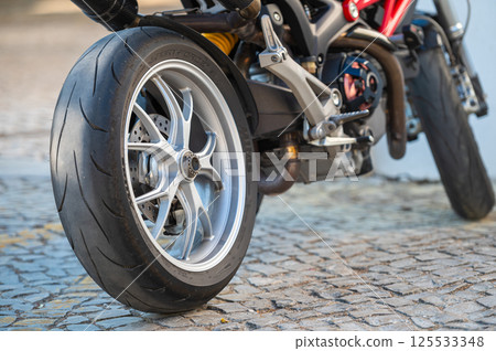 Close-up view of a motorcycle tire on cobblestone pavement during daylight Close-up view of a motorcycle tire on cobblestone pavement during daylight 125533348