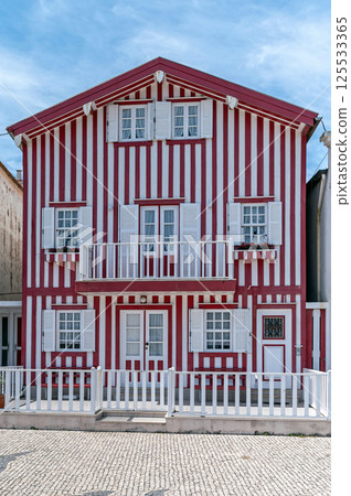 A traditional striped house stands proudly in a quiet coastal town under clear skies. Costa Nova A traditional striped house stands proudly in a quiet coastal town under clear skies. Costa Nova 125533365
