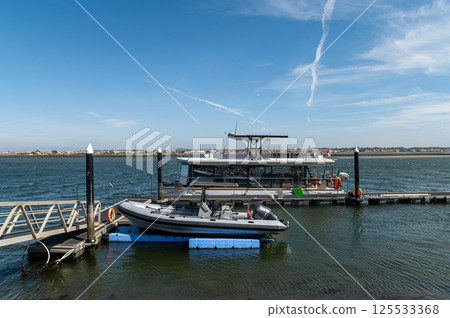A tourist boat is moored at a pier with clear skies over the water. 125533368