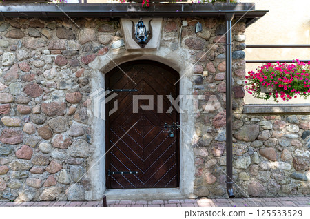 This sturdy wooden door features iron accents and is framed by a weathered stone wall. This sturdy wooden door features iron accents and is framed by a weathered stone wall. 125533529