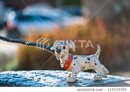 A playful decorative dog statue on a leash at a sunny park during the afternoon A playful decorative dog statue on a leash at a sunny park during the afternoon 125533705