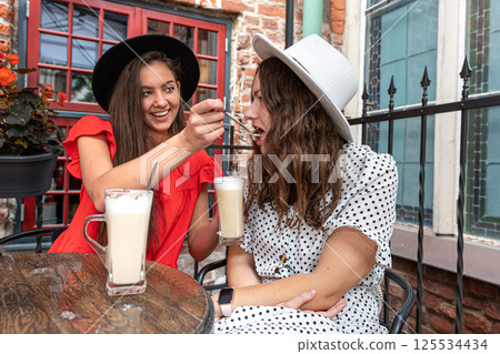 two cheerful charming young women talking and laughing in outdoor cafe, girls party concept 125534434
