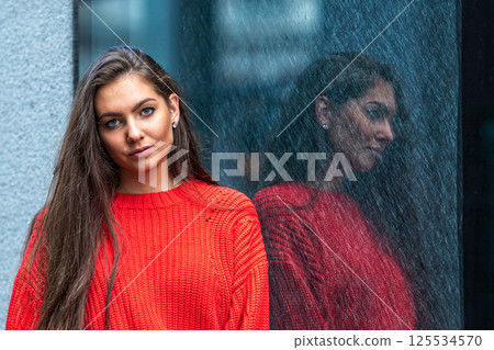 portrait of a young sensual brunette in a red sweater by a polished dark marble wall portrait of a young sensual brunette in a red sweater by a polished dark marble wall 125534570