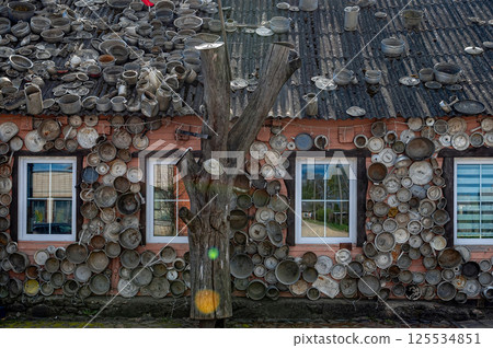 The pan house-puodu namas is covered with pots and pans of all shapes and sizes, closeup view 125534851