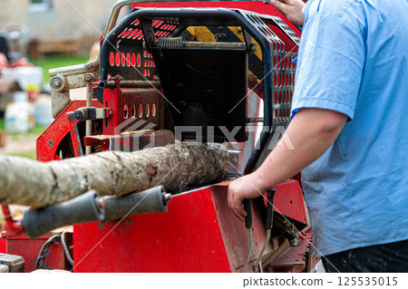 A man chops firewood with a wood chipper A man chops firewood with a wood chipper 125535015