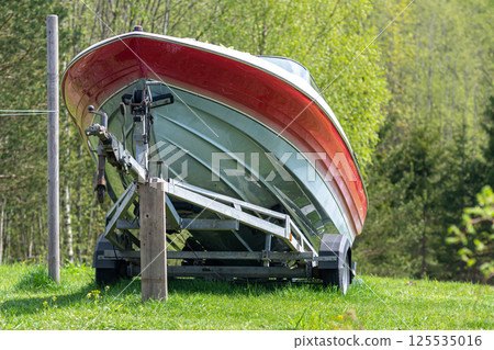 A motorboat on a trailer on a green meadow A motorboat on a trailer on a green meadow 125535016