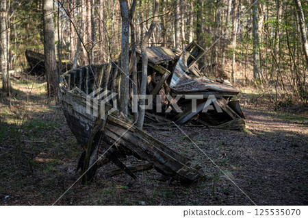 Old abandoned wooden fishing boat in the forest. Boats cemetery. Old abandoned wooden fishing boat in the forest. Boats cemetery. 125535070