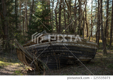 Old abandoned wooden fishing boat in the forest. Boats cemetery. 125535073