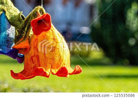 A handmade felt flower hangs in the garden on a sunny day 125535086