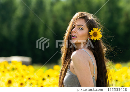 young woman with long hair in linean country style dress walks through a field of sunflowers 125535428