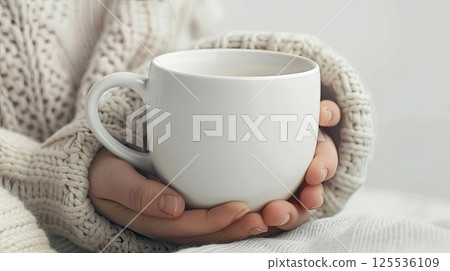 Close-up of hands in a warm sweater holding a white mug. Cozy mock up Close-up of hands in a warm sweater holding a white mug. Cozy mock up 125536109