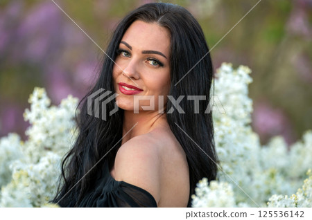 Woman with long black hair posing in a garden. Background with selective focus and copy space Woman with long black hair posing in a garden. Background with selective focus and copy space 125536142