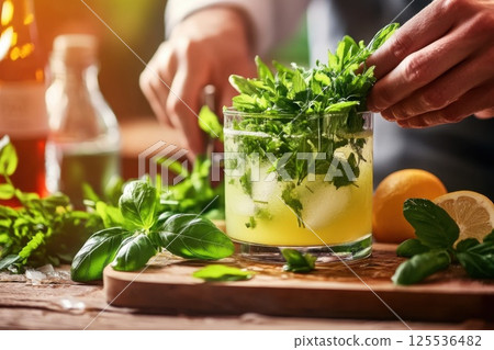 Bartender preparing a fresh cocktail with herbs in a vibrant bar setting at evening time 125536482