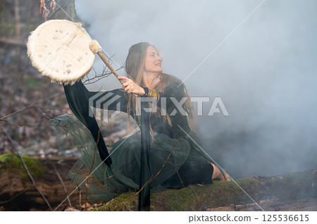Woman playing drum in foggy forest. Shallow depth of feld 125536615