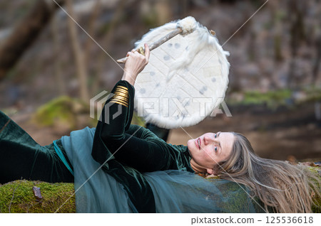 Woman playing a drum in a forest. Shallow depth of feld 125536618