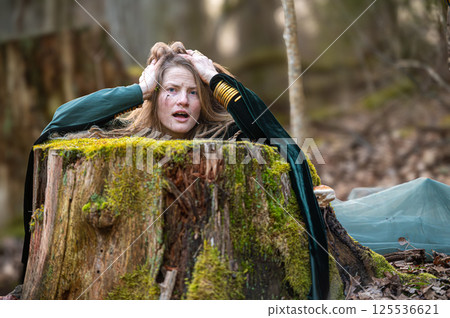 Woman trapped in tree stump in forest. Shallow depth of feld Woman trapped in tree stump in forest. Shallow depth of feld 125536621